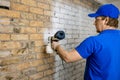 Construction worker painting old brick wall in white color with paint sprayer Royalty Free Stock Photo