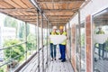 Construction worker and builder on scaffolding reading the plan