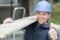 construction worker carrying wood plank shows thumb up Royalty Free Stock Photo