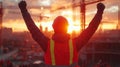 A construction worker celebrates a successful day at sunset with raised arms Royalty Free Stock Photo