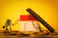 Construction worker with chains on his house on coin stacks - concept of debts and loans