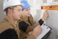 Construction worker checks level while supervison writes it down Royalty Free Stock Photo