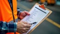 Construction worker checks safety checklist on clipboard. Worker wears high-visibility vest. Focuses on compliance on job site.