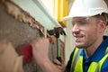 Construction Worker With Chisel Removing Plaster From Wall In Renovated House