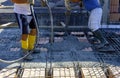 Construction worker compacting liquid cement in reinforcement form