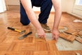 Construction worker and Handyman is removing old wooden parquet flooring using yellow hammer and scraping tool.