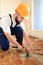 Construction worker and Handyman is removing old wooden parquet flooring using yellow hammer and scraping tool.