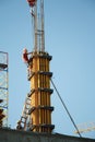 A construction worker controls the crane movement when assembling building blocks against a blue sky