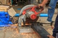 Construction worker cuts hollow steel square tube with circular saw