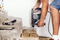 Construction worker drilling holes in wooden board and concrete using professional machinery