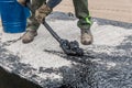 A construction worker is engaged in dirty manual work to repair and apply black bitumen waterproofing tar to the concrete surface