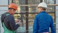 Construction worker and engineer talking at construction site site, rear view. Royalty Free Stock Photo