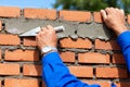 Bricklayer using a trowel to apply mortar to a new brick wall Royalty Free Stock Photo