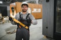 Construction worker gesturing thumbs up holding level in modular house production workshop Royalty Free Stock Photo