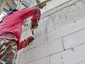 A construction worker hammering a nail down to attach wire mesh onto the brick before applying cement plastering on the wall