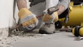 Construction worker hands with gloves working with hammer and chisel to remove old plaster from wall for house renovation, close Royalty Free Stock Photo