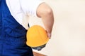 Construction worker and handyman at construction site with protective uniform, coverall and yellow helmet holding in hand. Royalty Free Stock Photo