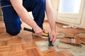 Construction worker and Handyman is removing old wooden parquet flooring using yellow hammer and scraping tool.