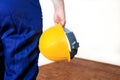 Construction worker at construction site with protective uniform and equipment, coverall and yellow helmet holding in hand. Royalty Free Stock Photo