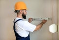 Construction worker is working on renovation of apartment. Builder is measuring and checking wall room using spirit level tool. Royalty Free Stock Photo
