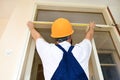 Construction worker and handyman is working on renovation of apartment. Builder is measuring of room door using measure tape. Royalty Free Stock Photo