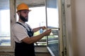 Construction worker and handyman is working on renovation of apartment. Builder is measuring window using measure tape. Royalty Free Stock Photo