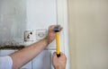 Construction worker and handyman with yellow hammer strikes and nails a nail into wooden wall of kitchen door at construction site Royalty Free Stock Photo