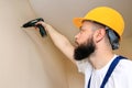 Construction worker works on renovation of apartment. Builder using electric screwdriver and screwing screw out of wall. Royalty Free Stock Photo