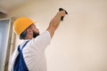 Construction worker works on renovation of apartment. Builder using electric screwdriver and screwing screw out of wall. Royalty Free Stock Photo