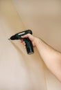 Construction worker works on renovation of apartment. Builder using electric screwdriver and screwing screw out of wall. Royalty Free Stock Photo