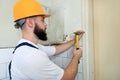 Construction worker and handyman with yellow hammer strikes and nails a nail into wooden wall of kitchen door at construction site Royalty Free Stock Photo