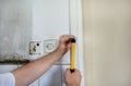 Construction worker and handyman with yellow hammer strikes and nails a nail into wooden wall of kitchen door at construction site Royalty Free Stock Photo