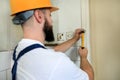 Construction worker and handyman with yellow hammer strikes and nails a nail into wooden wall of kitchen door at construction site Royalty Free Stock Photo