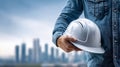 A construction worker with a hard hat in hand, ready for work in a cityscape. Royalty Free Stock Photo