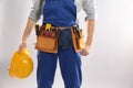 Construction worker with hard hat and tool belt on light background. Space for text Royalty Free Stock Photo