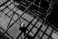 A construction worker in a hard hat walks through a scaffolding structure, their shadow cast across the concrete floor Royalty Free Stock Photo