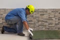 Construction worker with helmet while rolling out a roll of tarred bituminous sheath