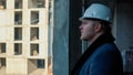 A construction worker in a helmet standing sideways, looking at the structural Royalty Free Stock Photo