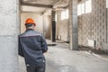 A construction worker in a helmet stands with his back to the camera, leaning on a reinforced concrete structure Royalty Free Stock Photo