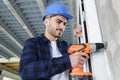 construction worker in helmet uses electric screwdriver