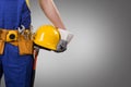 Construction worker holding helmet on gray background