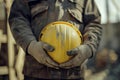 Construction worker holding yellow hard hat with hands covered in dust Royalty Free Stock Photo