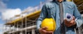 The construction worker holding plans and a helmet at a building site.AI generated image Royalty Free Stock Photo