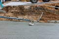 This worker is holding a steel trowel and smoothing out the plastering of a new sidewalk on a freshly laid concrete slab Royalty Free Stock Photo