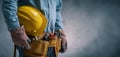 The construction worker holding a yellow helmet and tool belt in a professional setting. AI generated image Royalty Free Stock Photo
