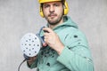 The construction worker holds a new grinder in his hand, close up