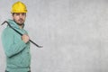 The construction worker holds a work tool in his hands, a crowbar