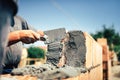 Construction worker installing brick masonry on exterior wall with trowel putty knife Royalty Free Stock Photo