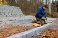 A construction worker installing concrete pavers stones on the construction site for the road sidewalk as a part of the Royalty Free Stock Photo
