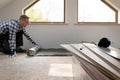 Construction worker installing laminate floor in a new renovated attic. Home improvement concept